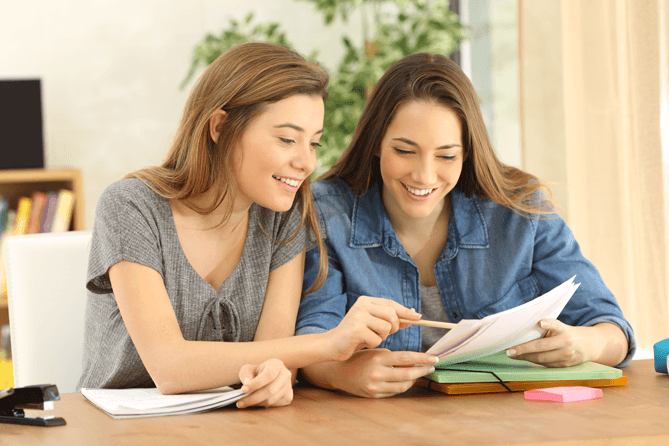 High school student with woman reading documents and smiling.